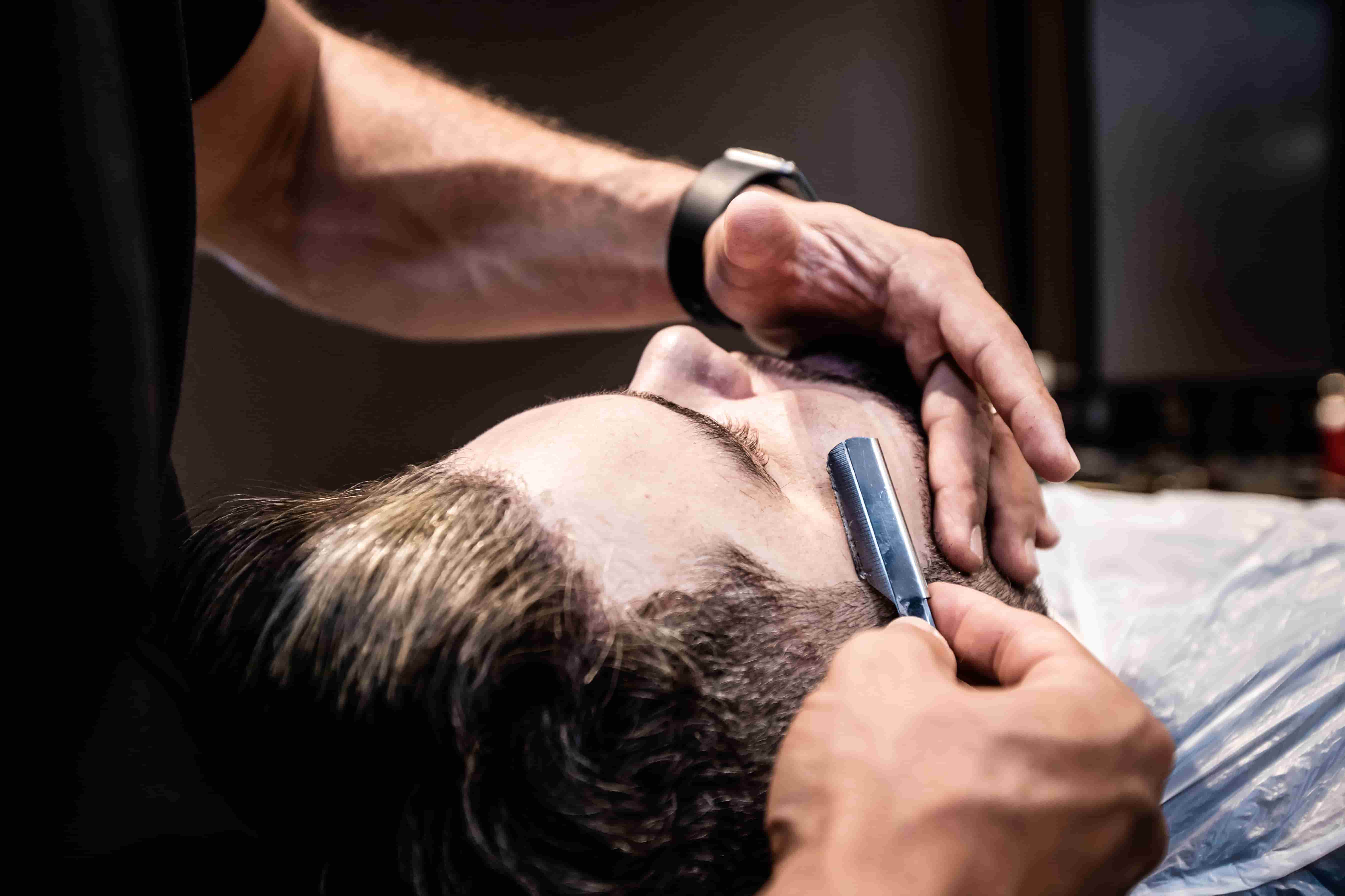 Barber giving a client a straight razor shave