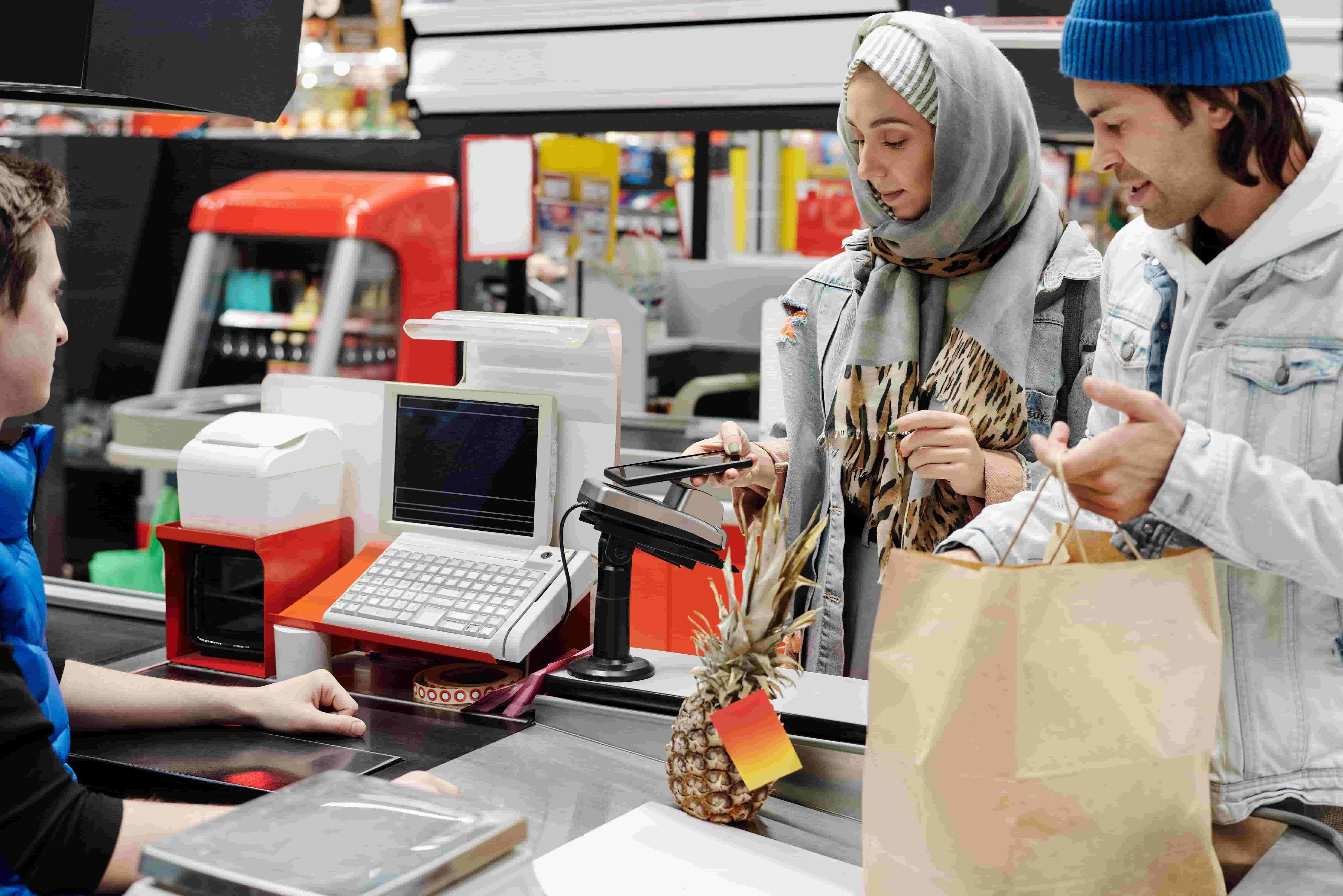 Customer paying by phone at a convenience store checkout counter
