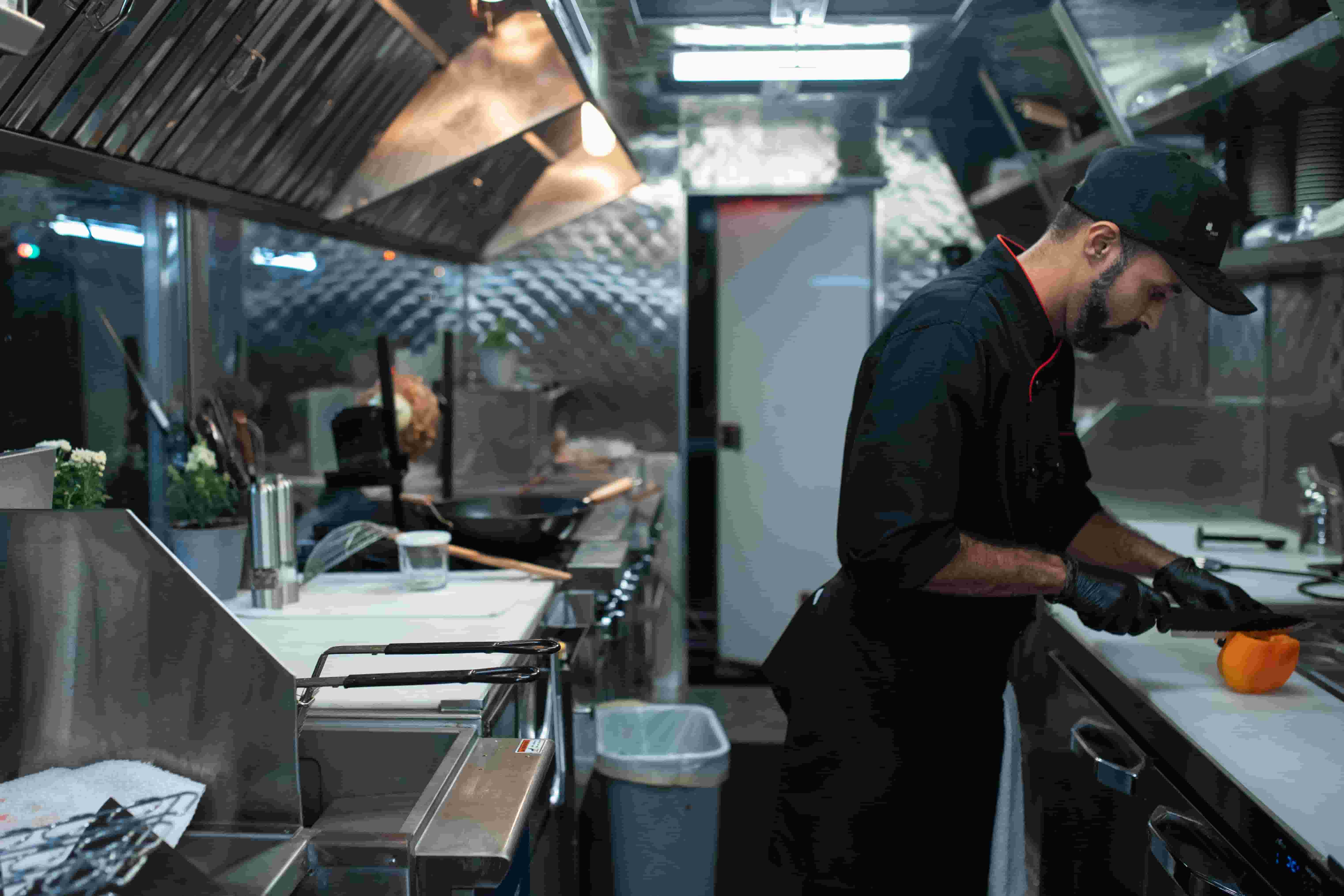 Cook preparing food on the prep line inside a food truck galley
