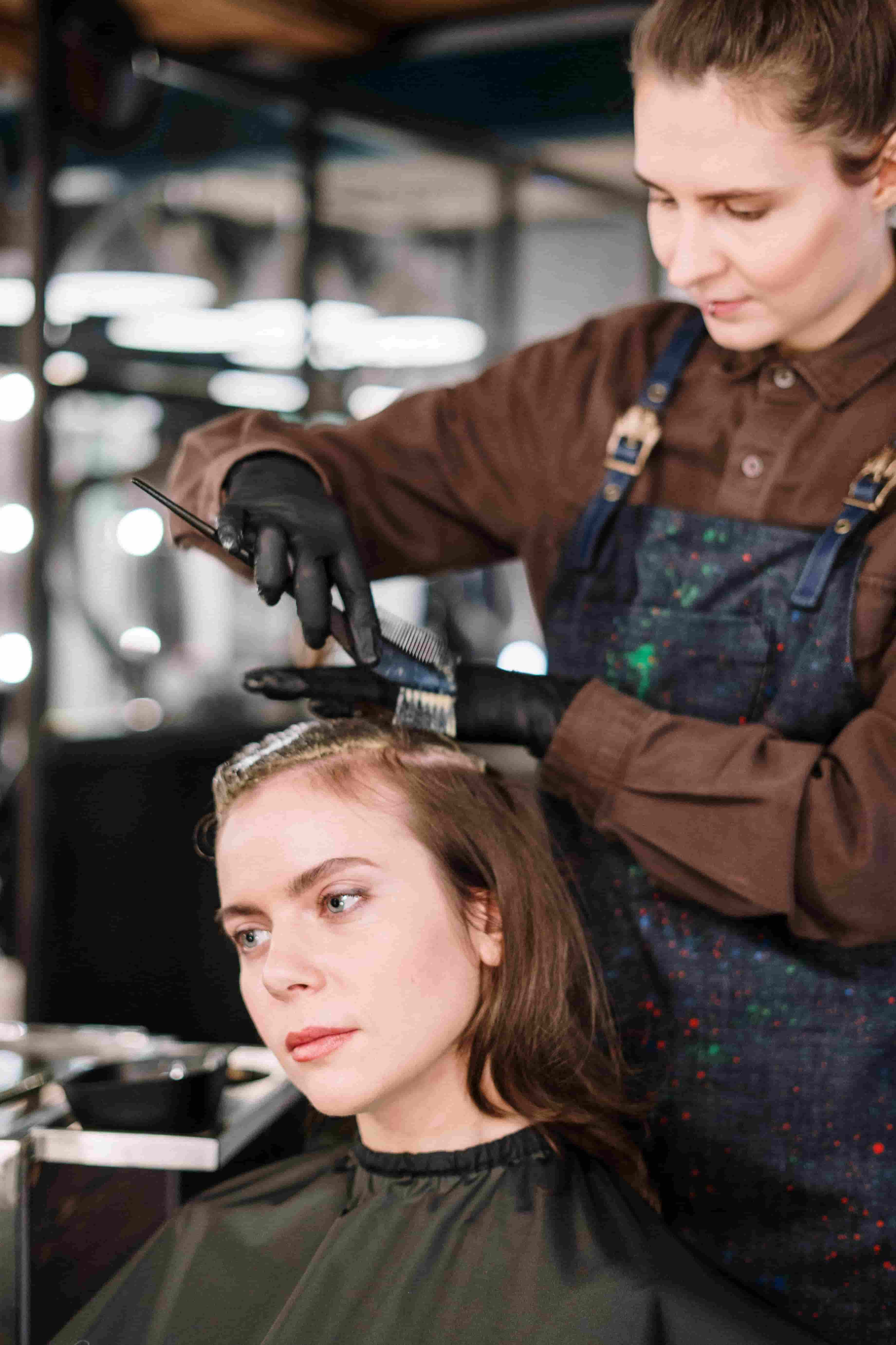 Hairstylist applying color to a client's hair in a salon