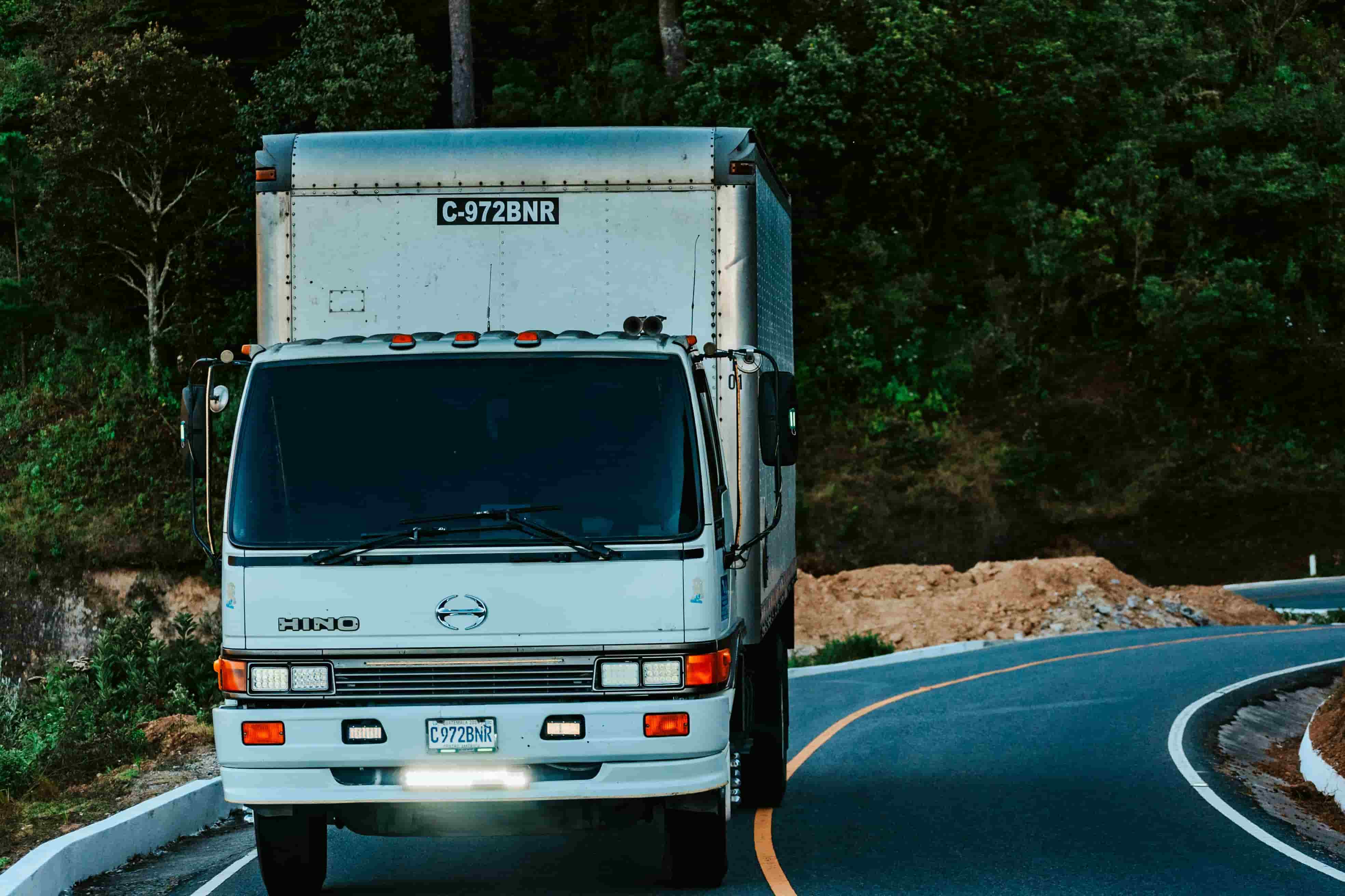 White box truck driving a winding mountain highway