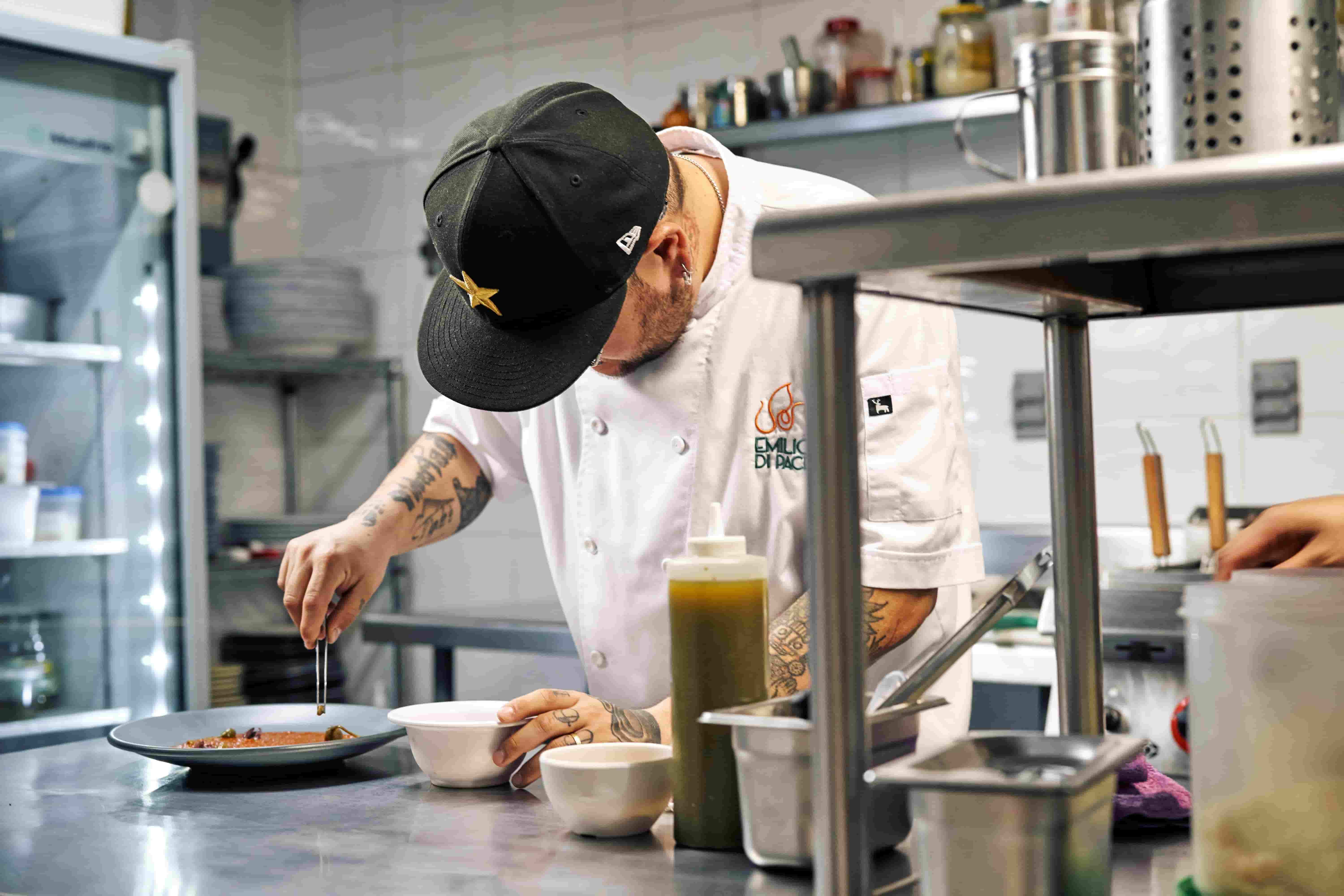 Chef plating a dish on the line in a commercial restaurant kitchen