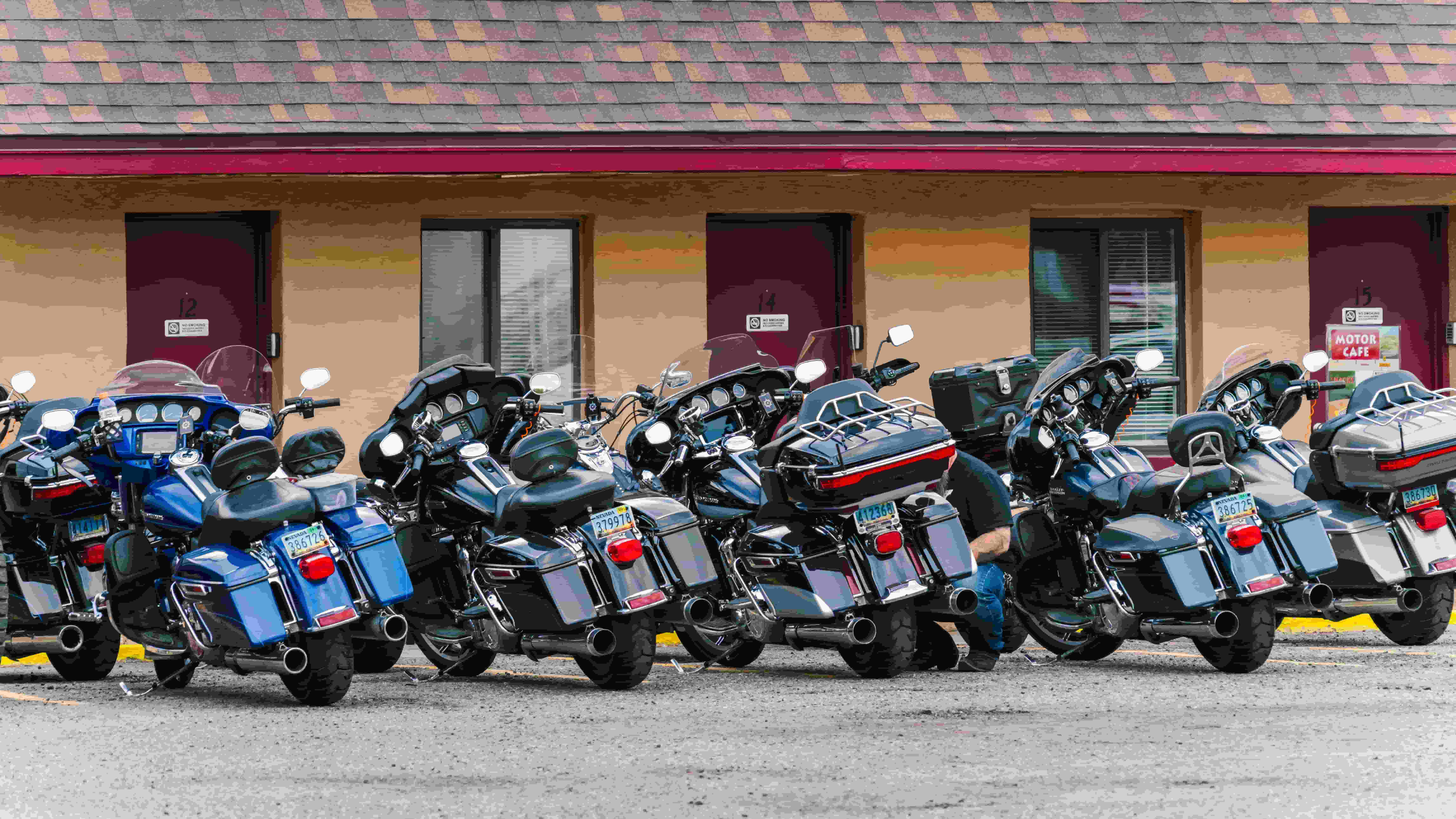Row of touring motorcycles parked outside a motel
