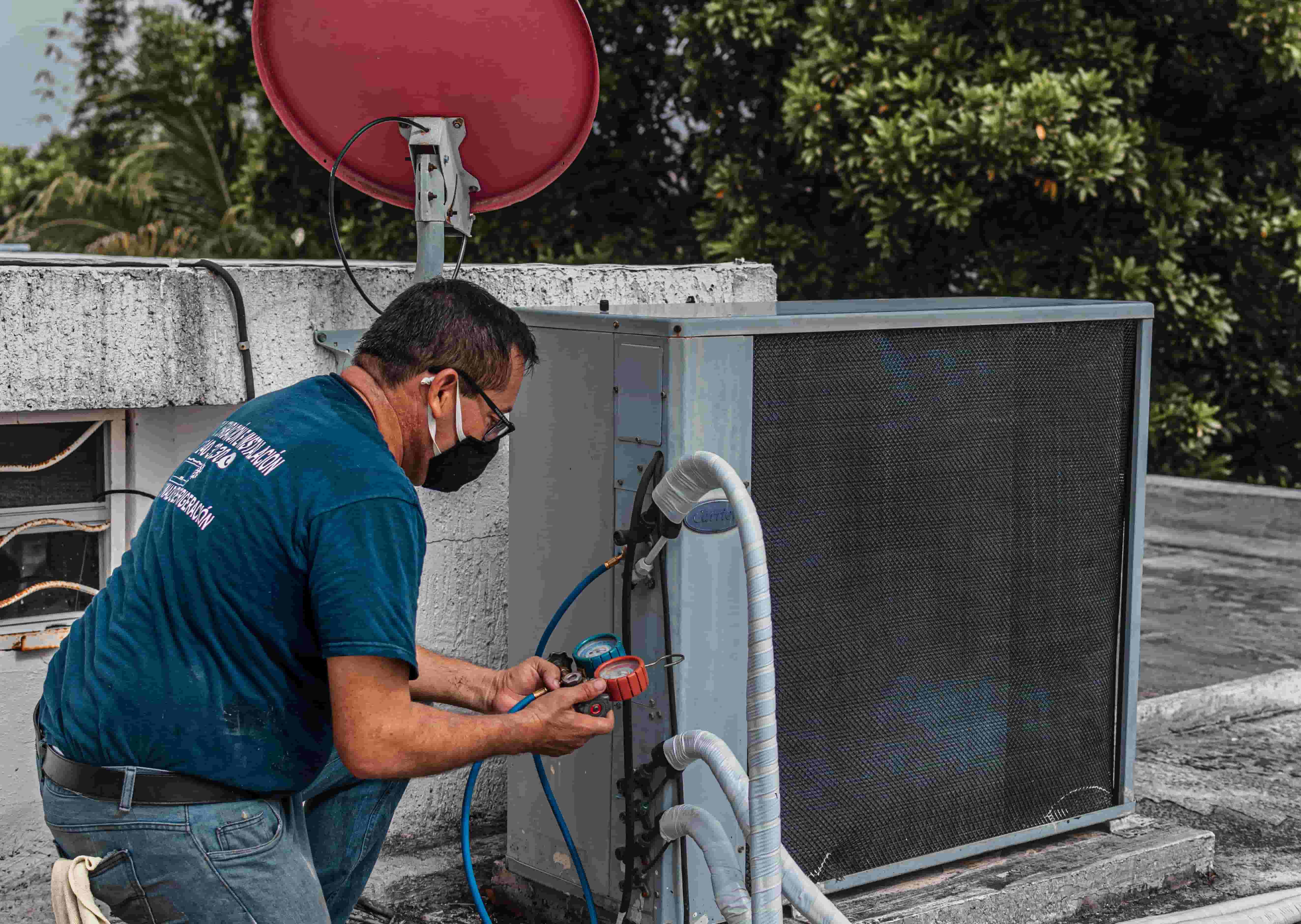 HVAC technician checking refrigerant pressures on a rooftop condenser unit