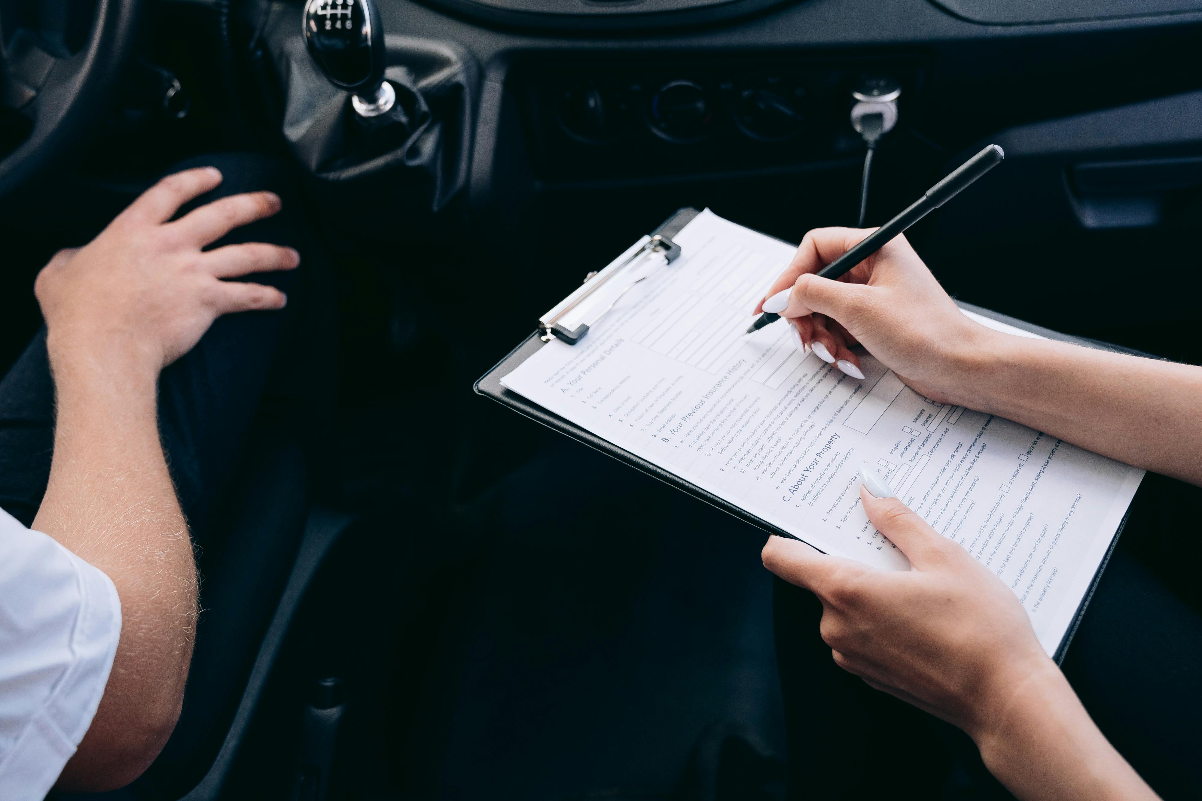Driver filling out an auto insurance application form in a parked car