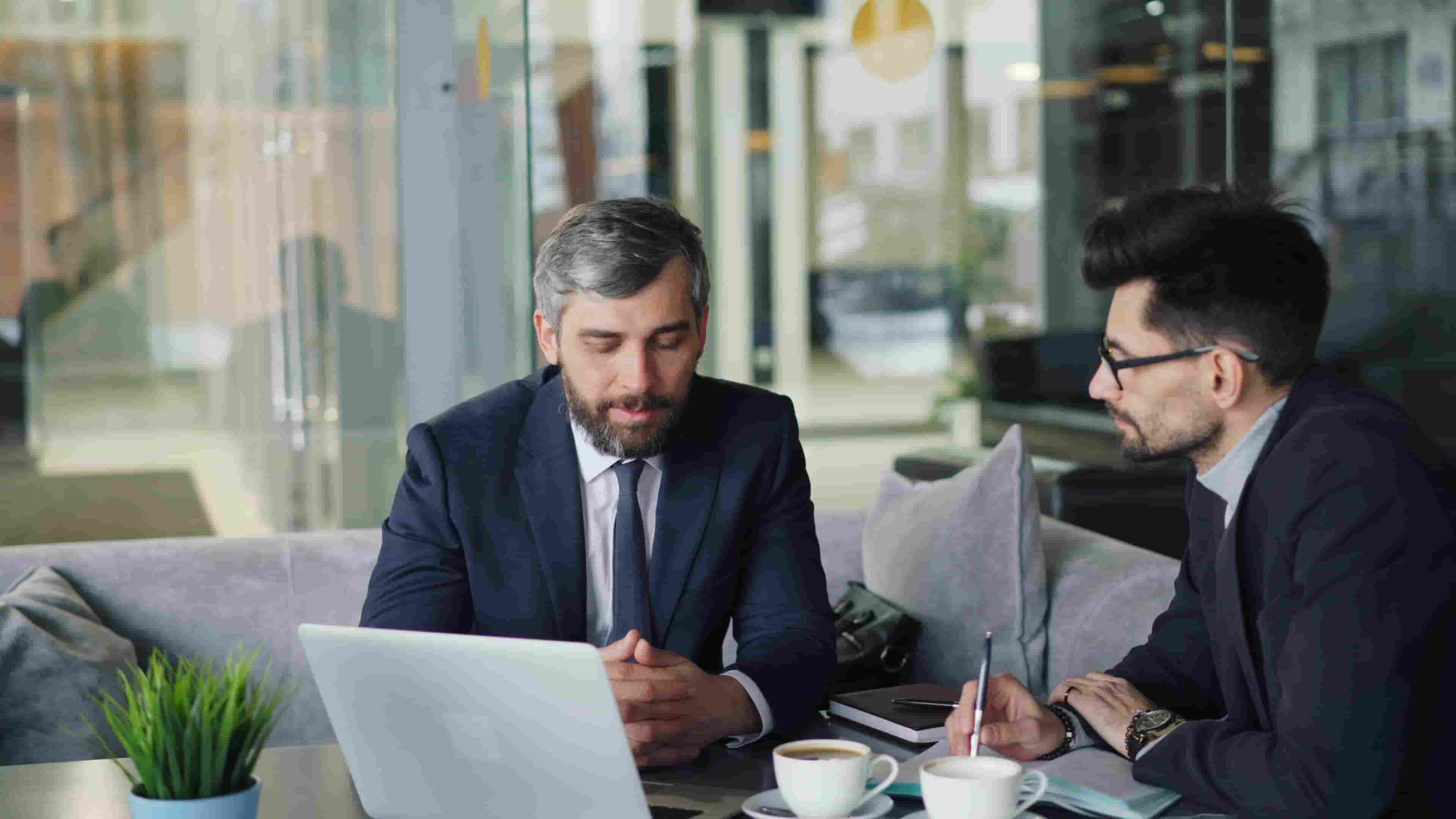 Two business professionals reviewing documents over coffee